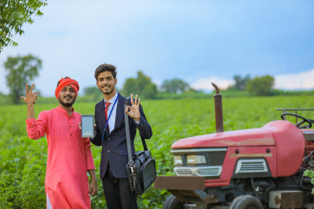 young indian agronomist showing smartphone with farmer